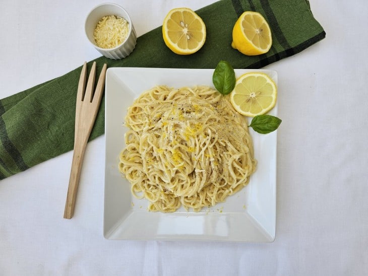 Spaghetti al limone pronto servido em um prato com algumas decorações de limão.