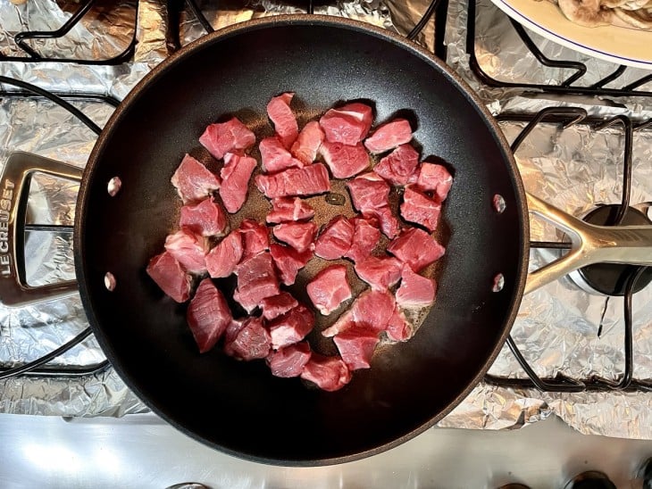 Uma frigideira com cubos de carnes.