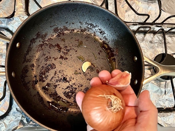 Uma frigideira com azeite, cebola e alho.