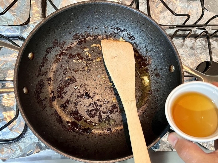 Uma frigideira com cebola, alho e conhaque.