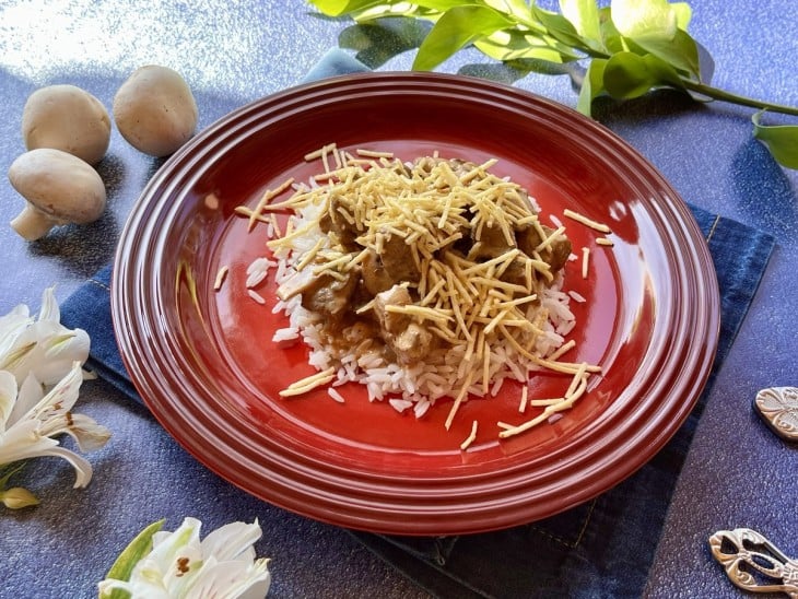 Um prato com arroz, strogonoff e batata palha.