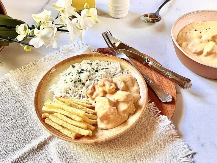 Prato composto por arroz, porção do strogonoff de camarão e porção de batatas-fritas.