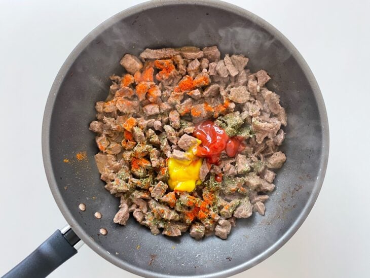 Temperos, mostarda e ketchup adicionados à carne.