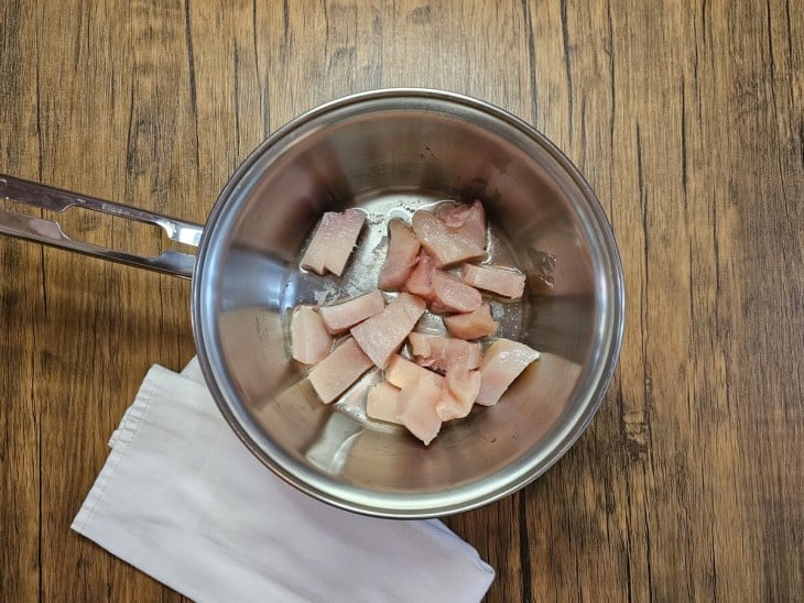 Uma panela contendo cubos de frango cru.