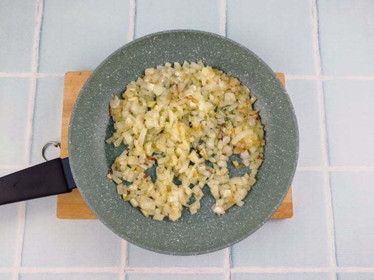 Cebola refogada em uma frigideira com um fio de azeite.