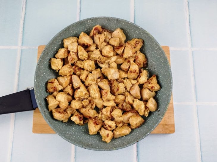 Cubos de frango dourados na frigideira.