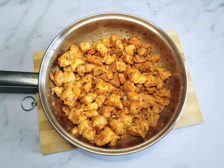 Uma frigideira com pedaços de frango dourados.