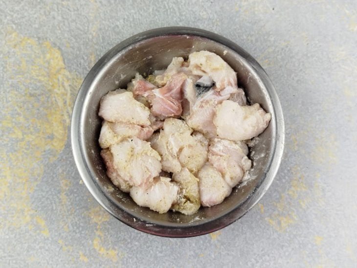 Peixe sendo temperado com sal e pimenta e envolvido com farinha.