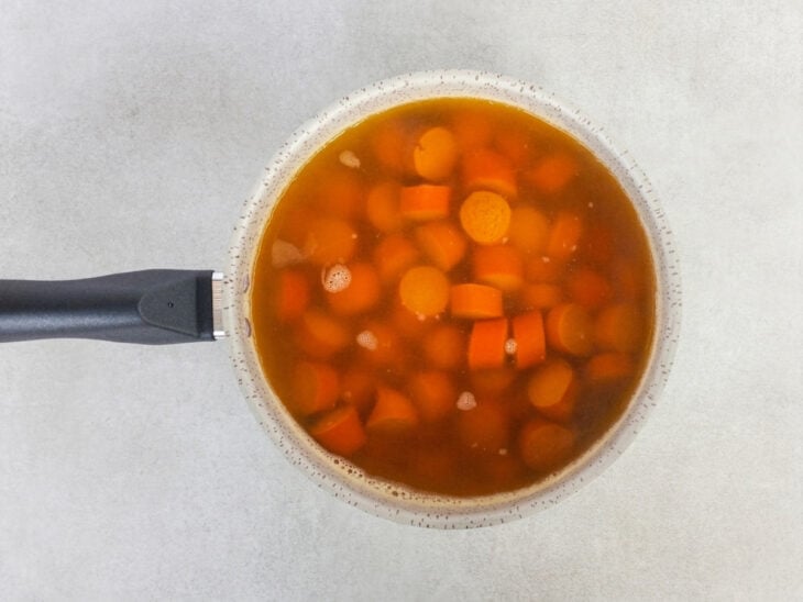 Rodelas de salsicha fervendo em uma panela com água no fogão.