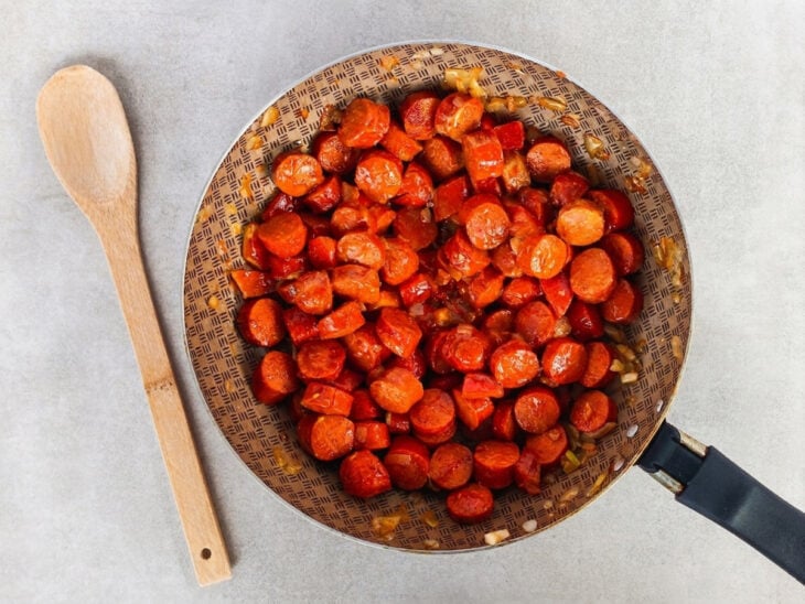 Tomate picado, extrato de tomate, ketchup e mostarda sendo adicionados à panela.