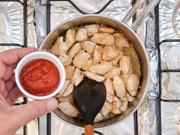 Molho de tomate zero e pimenta preta sendo despejados sobre o frango dourado na panela.