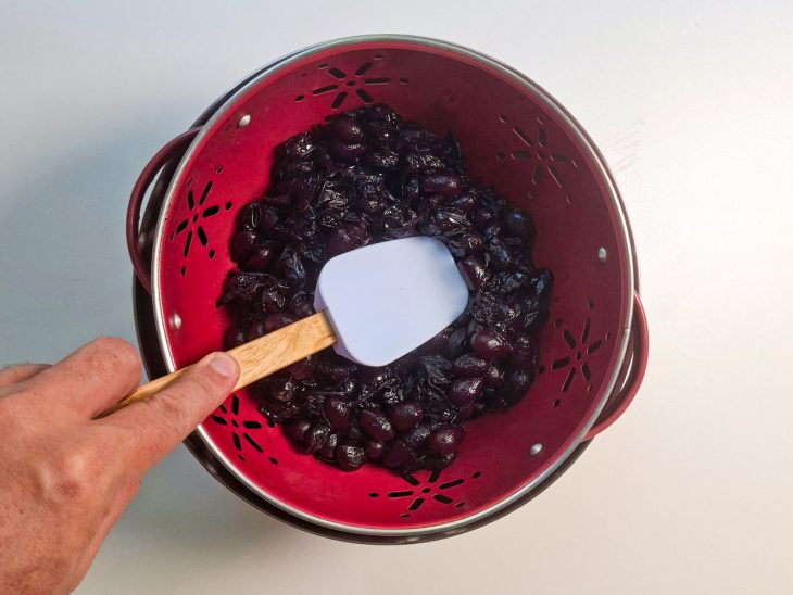Uvas sendo espremidas com uma espátula.