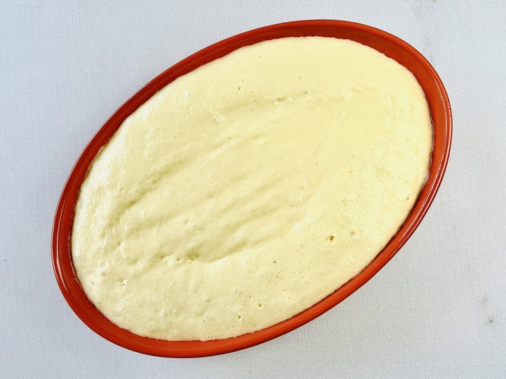 Mistura batida no liquidificador adicionada sobre a camada de chuchus na travessa.