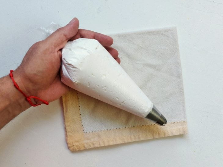 Um saquinho com bico de confeiteiro contendo a massa de suspiro.