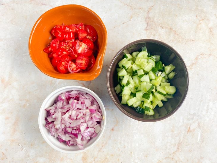 Tomates, cebola e pepino picados em potes separados.