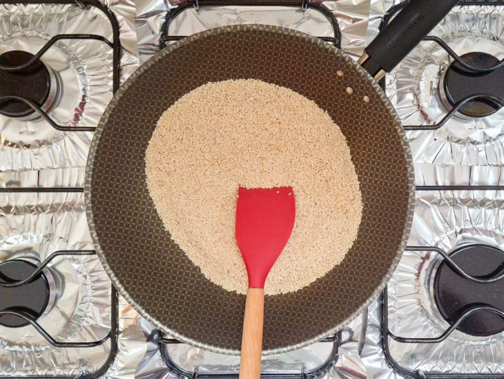 Grãos de gergelim sendo mexidos na panela.