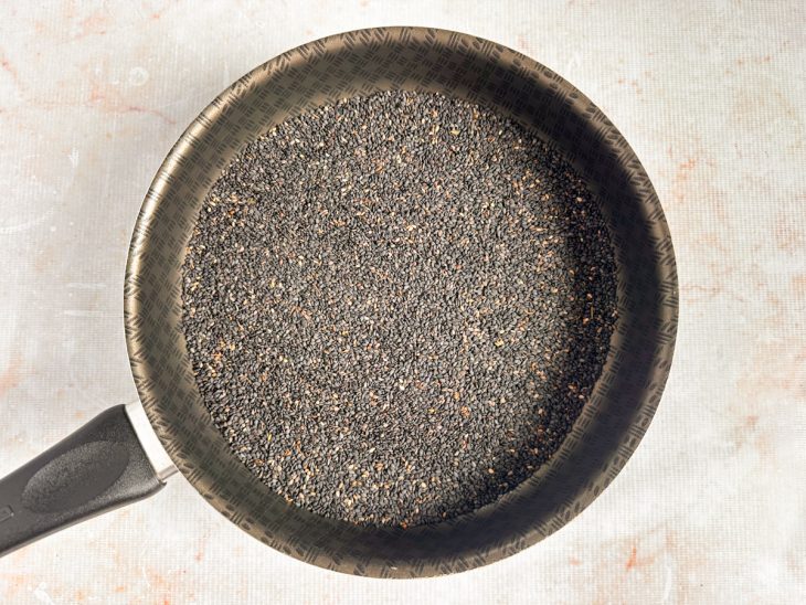 Gergelim sendo tostado em frigideira até soltar aroma.