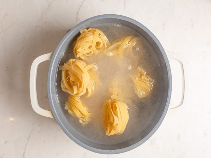 Uma panela com água e macarrão.