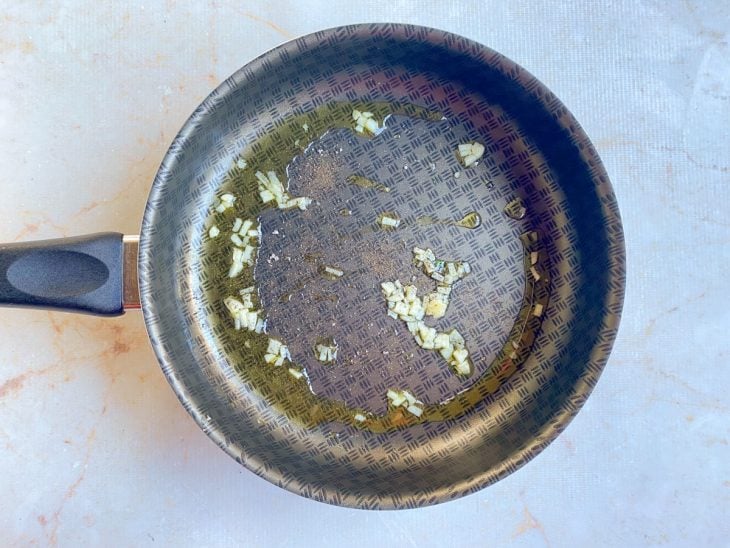 Uma frigideira com azeite, alho e temperos.