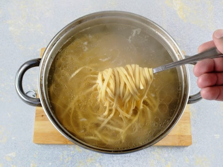 Porção de macarrão retirada com um garfo da panela para verificar o cozimento.