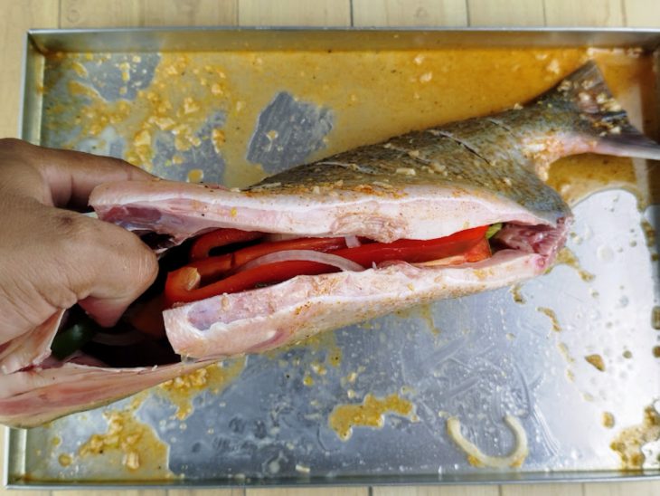 Pimentão e cebola colocados dentro do peixe.