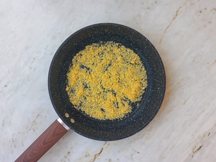 Queijo ralado espalhado ao fundo de uma frigideira.