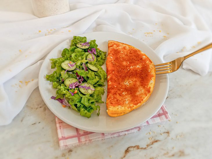 Tapioca com ovo pronta para consumo em um prato com salada.