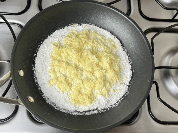 Uma frigideira contendo massa de tapioca com queijo ralado.