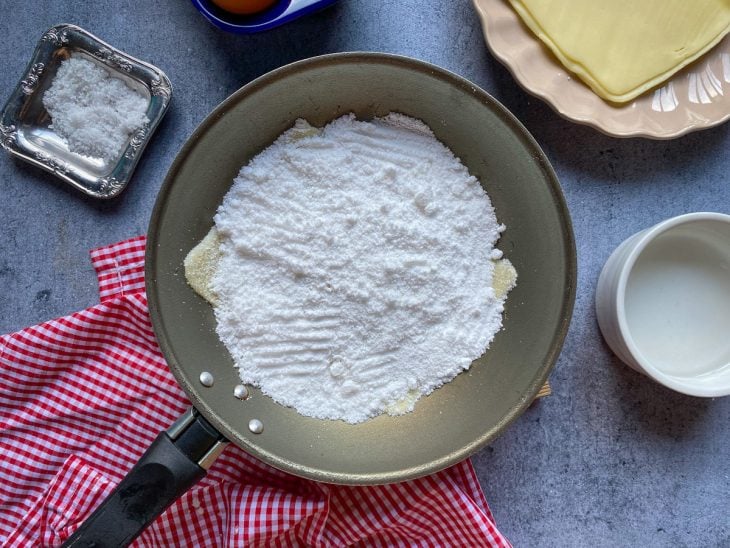 Uma frigideira com fatias de queijo e tapioca.