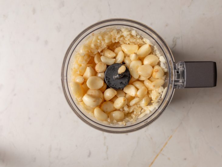 alho triturado em pasta e pedaços em processador de alimentos.