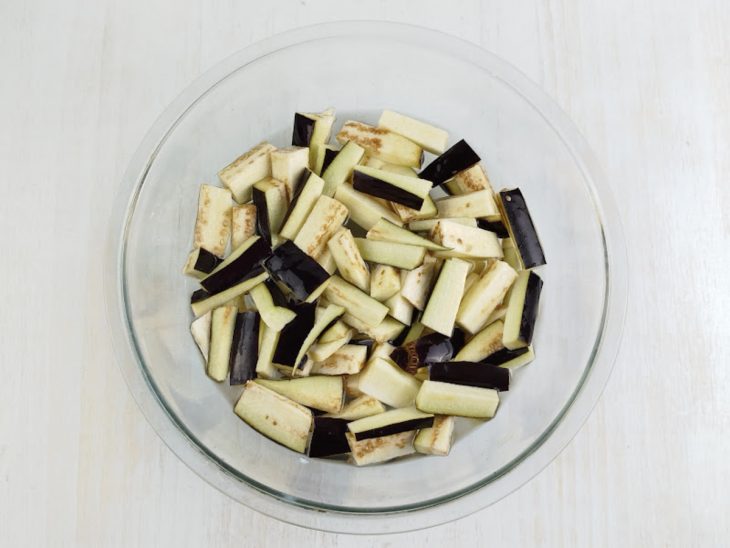 Berinjela cortada de molho em água numa tigela.