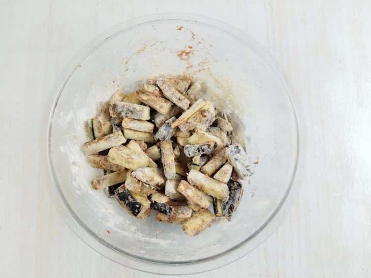 Farinha e temperos adicionados na tigela com berinjela.