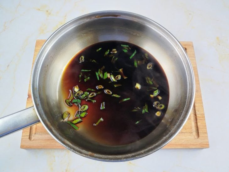 Shoyu, água, açúcar, sakê e cebolinha misturados em uma panela.