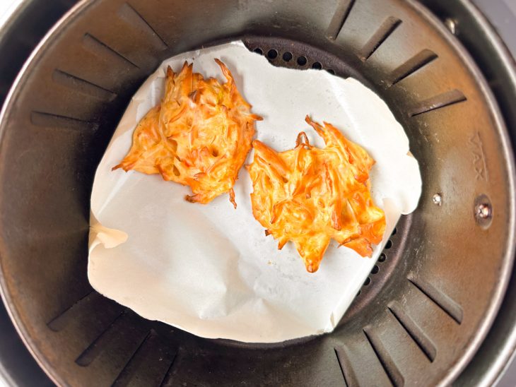 Tempurás dourados sendo retirados do cesto da air fryer.