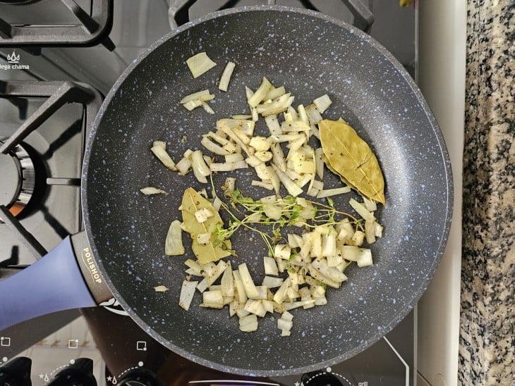 Uma frigideira contendo azeite, cebola, tomilho, louro e pimenta.