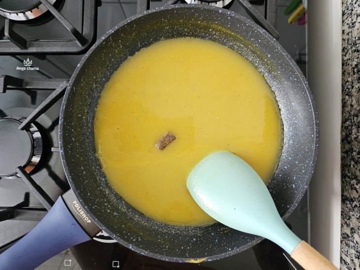 Uma frigideira contendo molho de laranja e tablete de caldo de bacon.