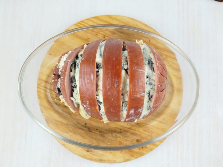 Tender com cortes profundos e queijos sendo inseridos entre as fatias.