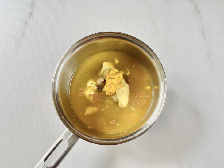 Panela com mel, açúcar mascavo, temperos e suco de laranja sendo misturados no fogo