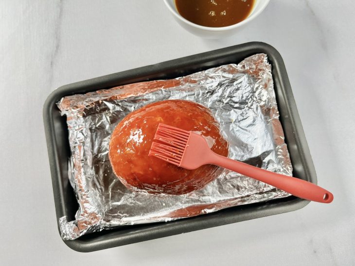 Tender sendo pincelado com metade do molho preparado.