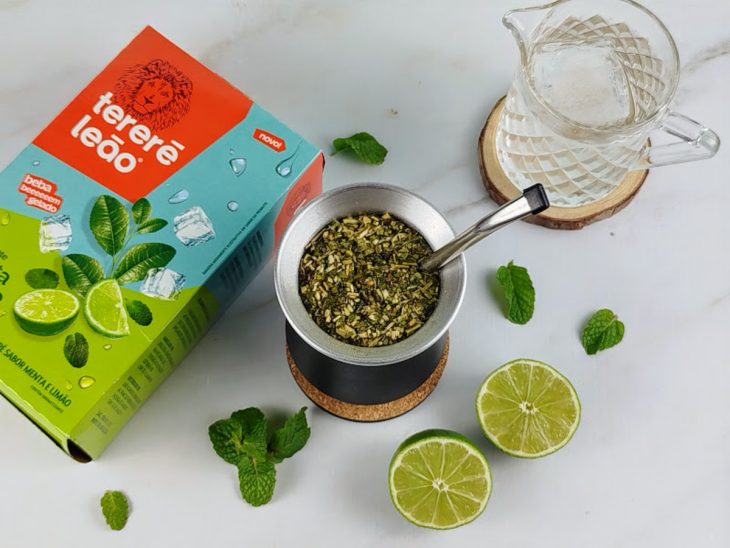 Copo de tereré, jarra de vidro com água e embalagem de erva mate sobre uma bancada.