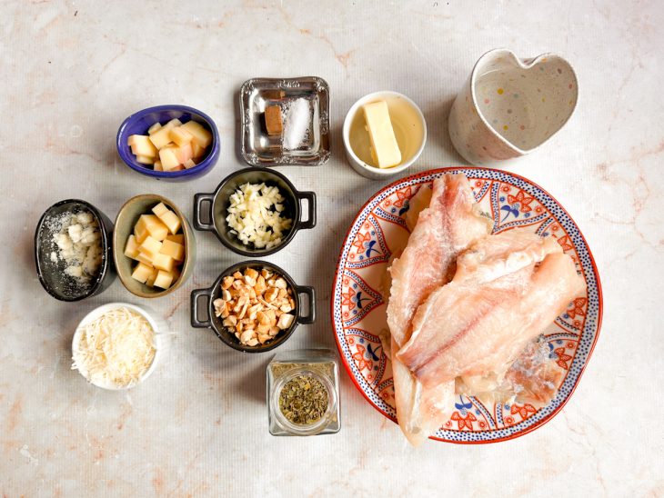 Ingredientes organizados sobre a bancada com queijos e ervas picados.