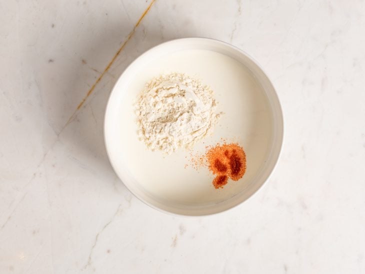 Um recipiente com creme de cebola, creme de leite e colorau.