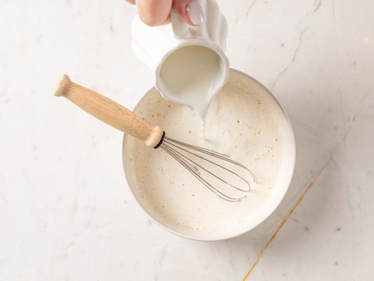 Um recipiente com a mistura de leite, creme de cebola, creme de leite e colorau.