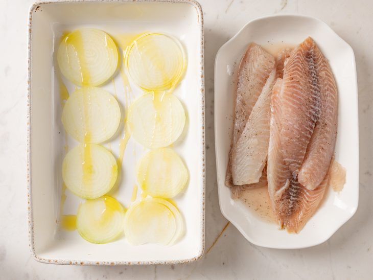 Um refratário com uma camada de cebolas e outro recipiente com os peixes marinados.