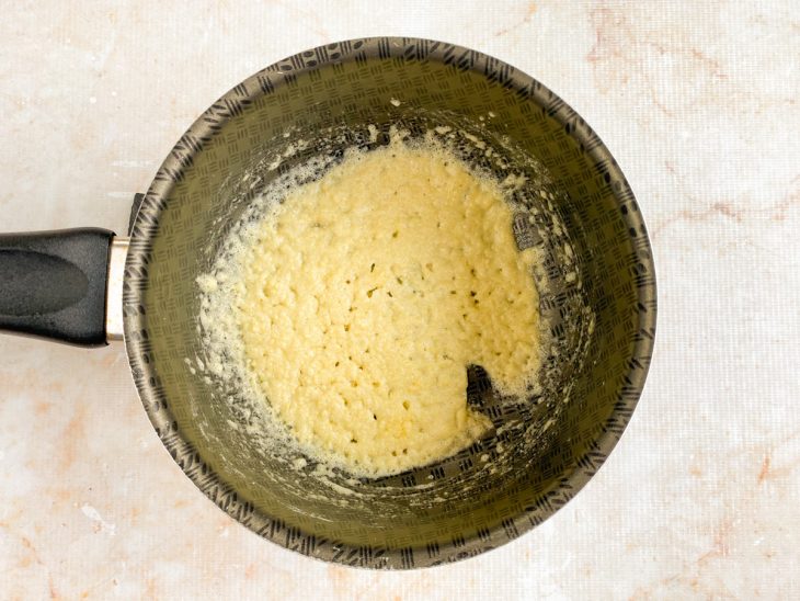 Na panela, o leite sendo incorporado na manteiga e farinha de trigo.