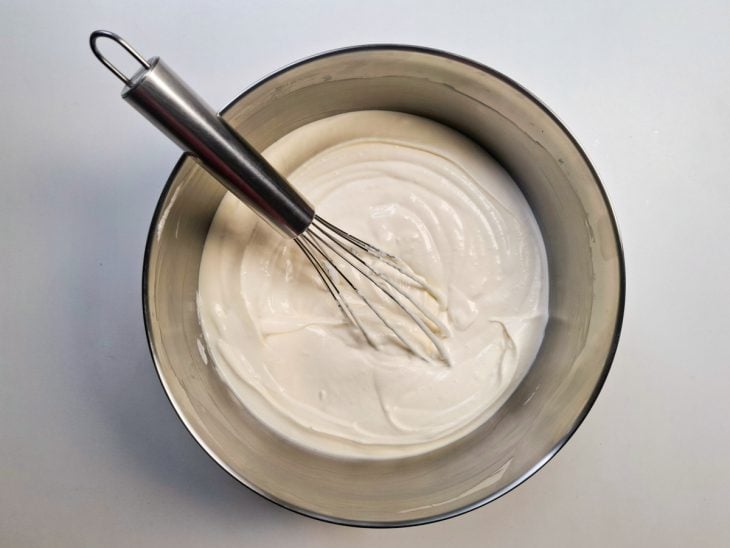 Queijo mascarpone, licor de amêndoas, creme de gemas, chantilly e merengue misturados em uma tigela de alumínio.