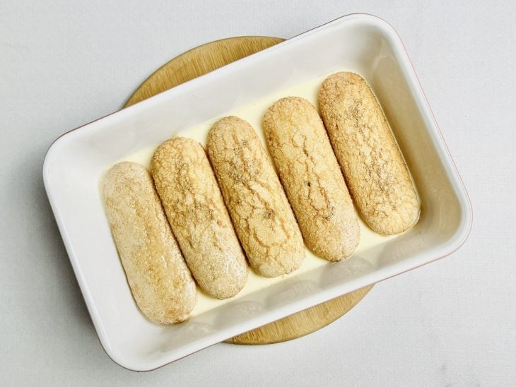 Bolachas umedecidas e acomodadas sobre a camada de creme no refratário.
