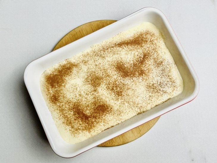 Camada de creme e chocolate em pó polvilhado na superfície.