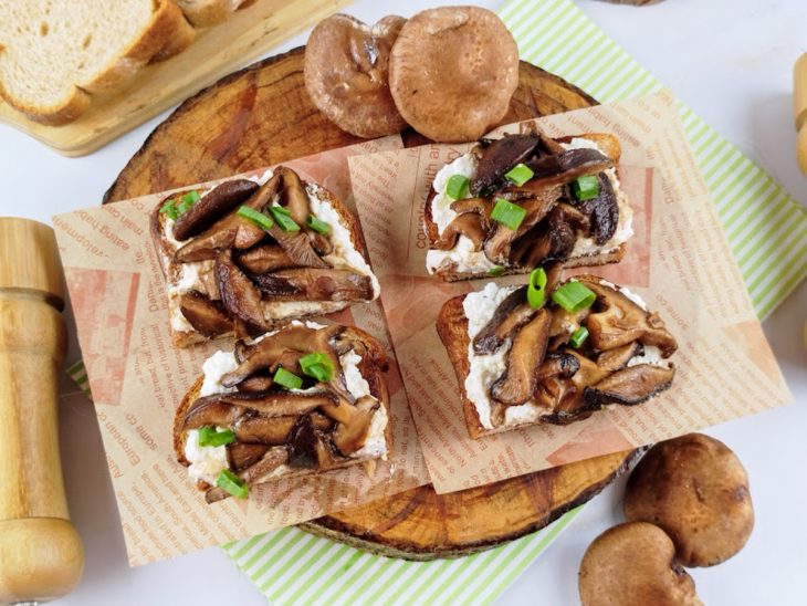 Uma tábua com toast de ricota com cogumelos.