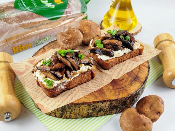 Uma tábua com toast de ricota com cogumelos.